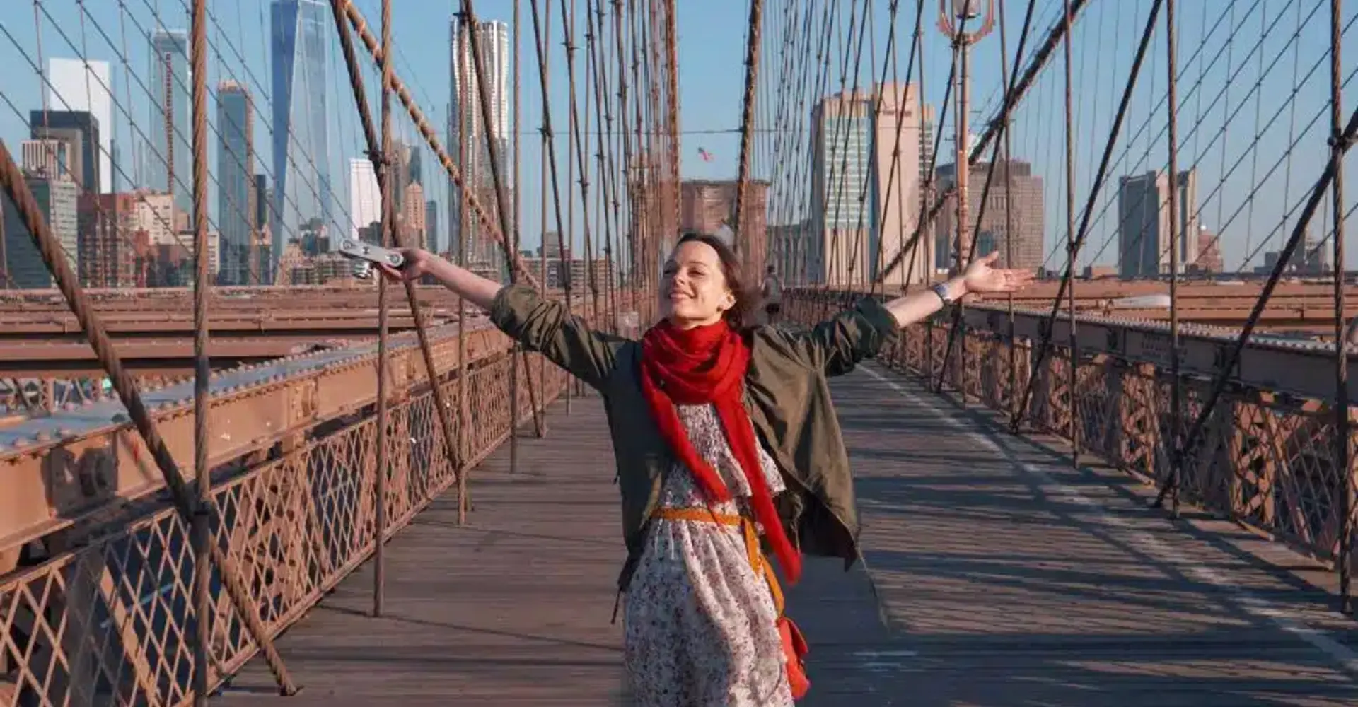 Participante con los brazos abiertos en el puente de Brooklyn con el skyline de Nueva York al fondo
