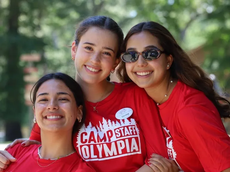 Consejeros de campamento con playera de staff, sonriendo al aire libre